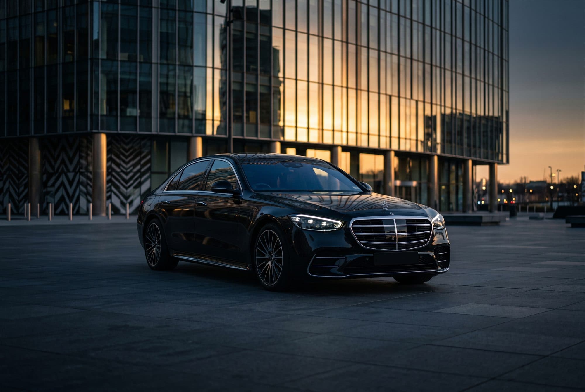 Donkere luxe sedan voor een modern kantoorgebouw van glas